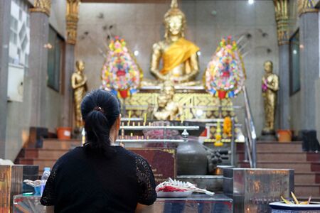 Rear view of Thai woman praying to Buddha in the templeの写真素材