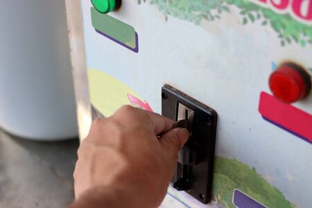 Close up view of hand of human inserting coin in to the old vending machine,Shallow depth of field, Automatic Machineの写真素材