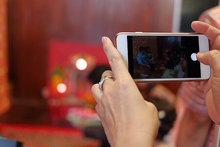 Hands of woman taking photo of Thai wedding ceremonyの写真素材