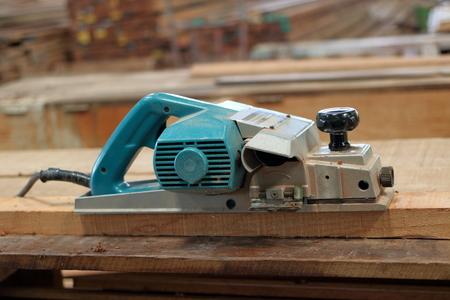 Electric planer on the wooden plank in carpentry workshop
