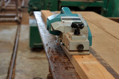 Front view of electric planer on the wooden plank in carpentry workshopの写真素材