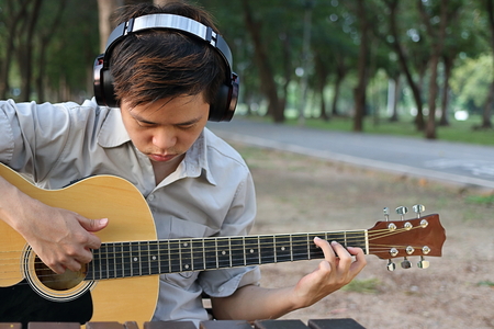 Portrait of musician or guitarist playing acoustic guitar in blurred nature with copyspace background.の写真素材