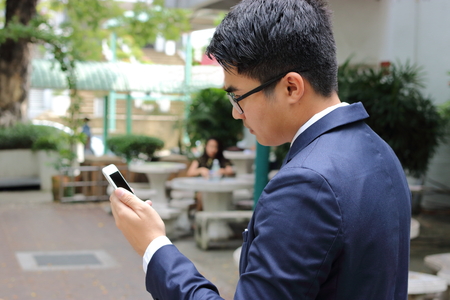Portrait of businessman holding mobile smartphone in the parkの写真素材