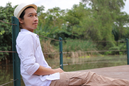 Portrait of young relaxed man sitting on the floor in out door background.の写真素材