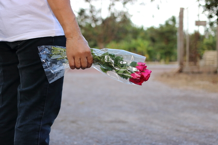 A beautiful bouquet of red roses is held by hand of middle aged woman. Valentine's day or romance date conceptの写真素材