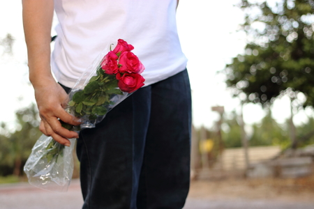 Woman holding bouquet of beautiful red roses on nature bokeh background. Romance and sweet Valentine's day conceptの写真素材