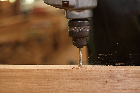 Close up electric drill is being worked with wooden board by worker. Selective focus and shallow depth of field.の写真素材