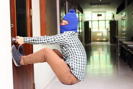 Masked burglar attempt to open the door before burglary. Criminal conceptの写真素材