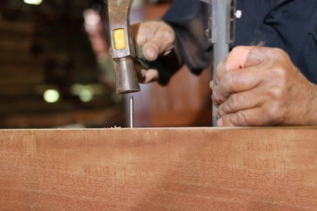 Close up hammer and nail using by carpenter on wooden board. Selective focus and shallow depth of field.の写真素材
