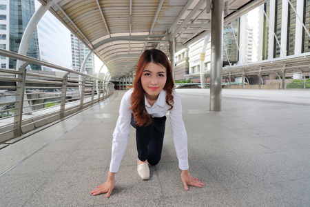 Young businesswoman in start position ready to run at urban outdoor public. Start up business concept.の写真素材
