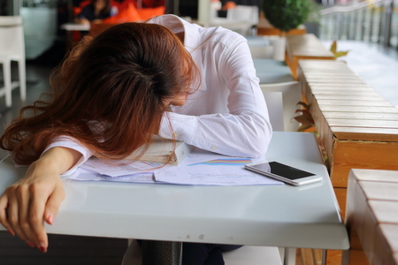 Portrait of tired and exhausted young businesswoman sleep at workplace in her office. Overwork business concept.の写真素材