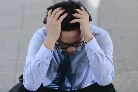 Close up frustrated stressed Asian business man touching head and feeling tired or sad his jobの写真素材