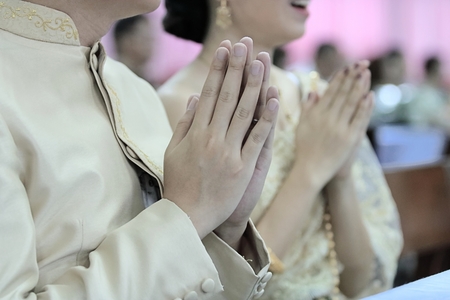 Hands of young couple praying in Thai wedding ceremony. Selective focus and shallow depth of field.の写真素材