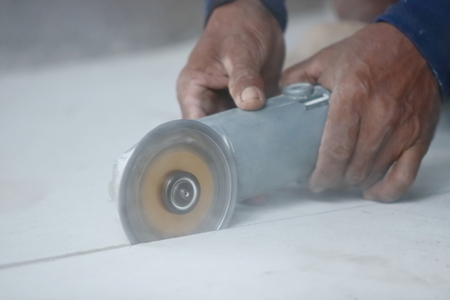 Close up angle grinder cutting concrete with hands of construction worker.の写真素材
