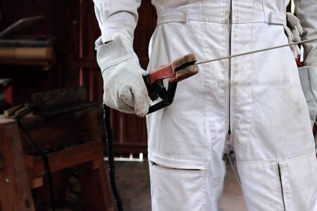 Close up hands of welder holding arc welding torch in workshop. Industrial concept.