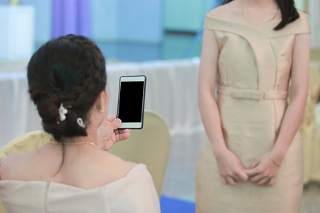 Woman taking a photo of young girl with mobile smart phoneの写真素材