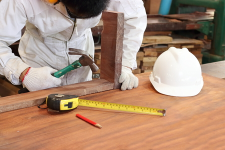 Professional carpenter with safety uniform holding hammer with other tools in carpentry workshop.の写真素材