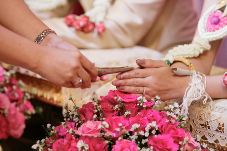 Guest pouring water with bride and groom hands in water relaunch ceremony. Thai traditional weddingの写真素材