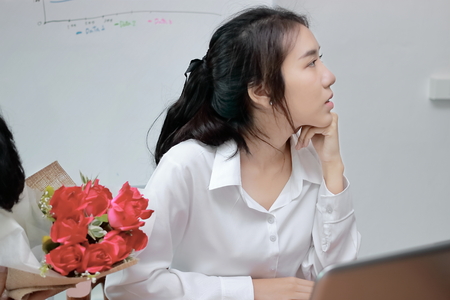 Cropped image of angry Asian woman refuses a bouquet of red roses from business man in office. Disappointed love concept.の写真素材