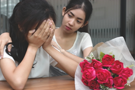 Vintage toned image of attractive Asian woman comforting a sad depressed female friend. Break up or best relationship concept.の写真素材