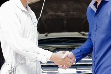 Mechanic and customer shaking hands after repair engine at auto service garage. Car sale or deal concept.の写真素材