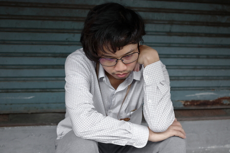 Frustrated stressed young Asian business man feeling disappointed or exhausted with job at outside office.の写真素材