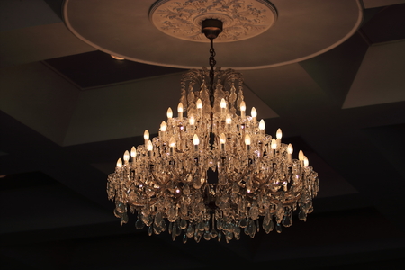Close up luxury crystal chandelier hanging under ceiling in the room.の写真素材
