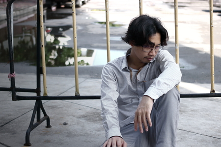 Tired overworked young Asian business man sitting on the floor.の写真素材