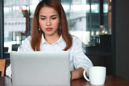 Attractive young Asian business woman with laptop working in modern office.の写真素材