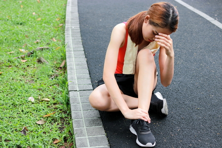 Young Asian fitness woman runner suffering from broken twisted ankle. Running injury accident concept.の写真素材