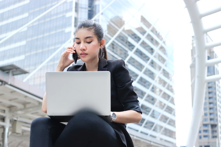 Attractive young Asian business woman working with laptop and mobile smart phone at outside office.の写真素材