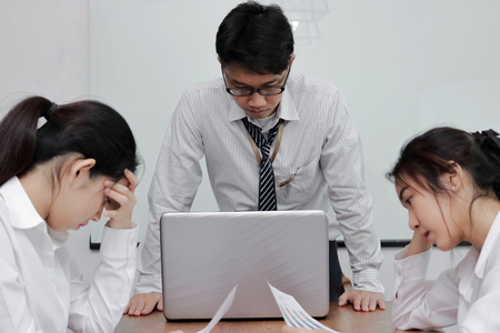 Depressed stressed young Asian business people suffering from severe problem during meeting in office.の写真素材
