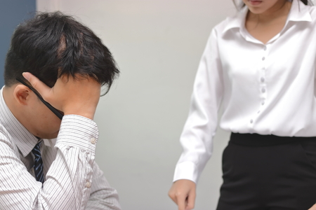 Angry woman boss blaming young Asian man with hands on face in office.の写真素材