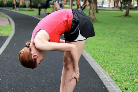 Healthy Asian woman stretching her legs before run in park. Fitness and exercise concept.の写真素材