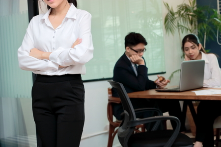 Leadership business woman concept. Cropped image of young Asian businesswoman standing against her colleague in office background.の写真素材