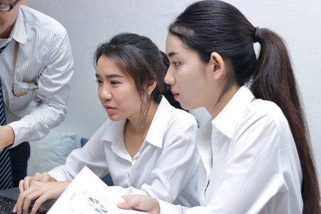 Asian business people with laptop working together in modern office. Selective focus and shallow depth of field.の写真素材