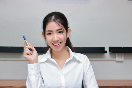 Successful young Asian business woman with pen having idea in workplace.の写真素材