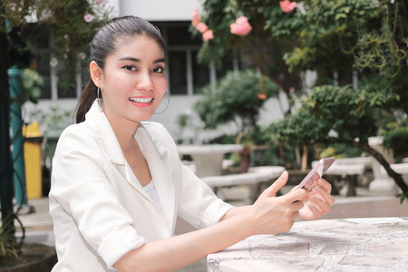 Smiling young Asian woman using mobile smart phone. Internet of things conceptの写真素材