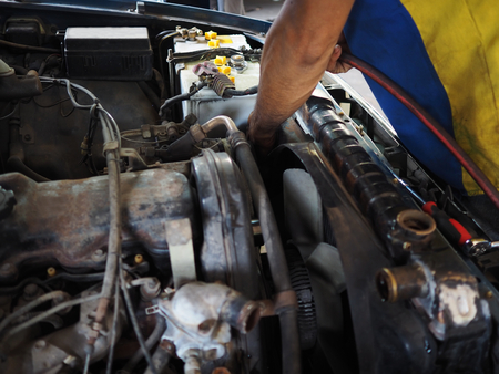 Mechanic man in uniform repairing car in garage. Auto repair service.