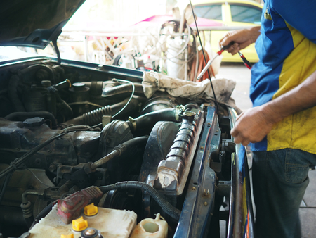 Mechanic man in uniform repairing car in garage. Auto repair service.の写真素材