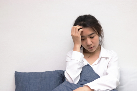 Anxiety depressed young Asian woman with hands on forehead suffering from trouble.の写真素材