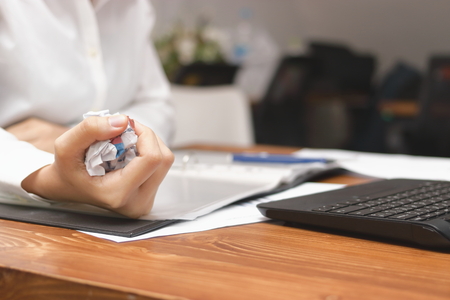 Hands of businesswoman holding crumpled paper on workplace in office. Failure and tired business concept.の写真素材