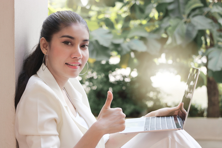 Young Asian business woman with laptop show thumb up hand. Internet of things concept.の写真素材