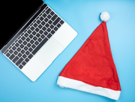 Top view of laptop and Santa hat on blue isolated background.の写真素材