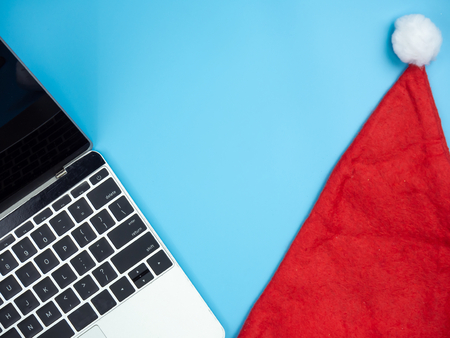 Top view of laptop and Santa hat on blue isolated background.の写真素材