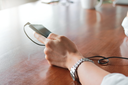Soft focus of hands of woman with phone listening music in living room.