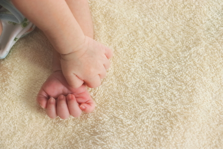 Little hands of newborn tiny Asian baby on a yellow blanketの写真素材