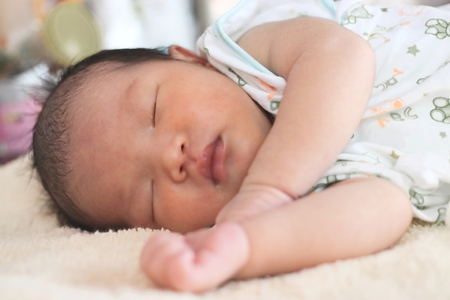 Cute newborn tiny Asian baby sleeping on the bedの写真素材