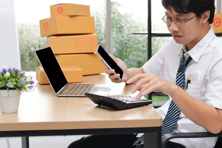 Young Asian entrepreneur owner chatting on phone at workplace at home. Start up small business.の写真素材