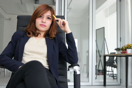 Confident young Asian executive woman sitting and having idea in workplace of office.の写真素材